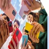 Circle of friends holding their phones together
