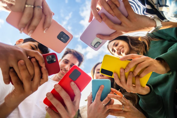 Circle of friends holding their phones together