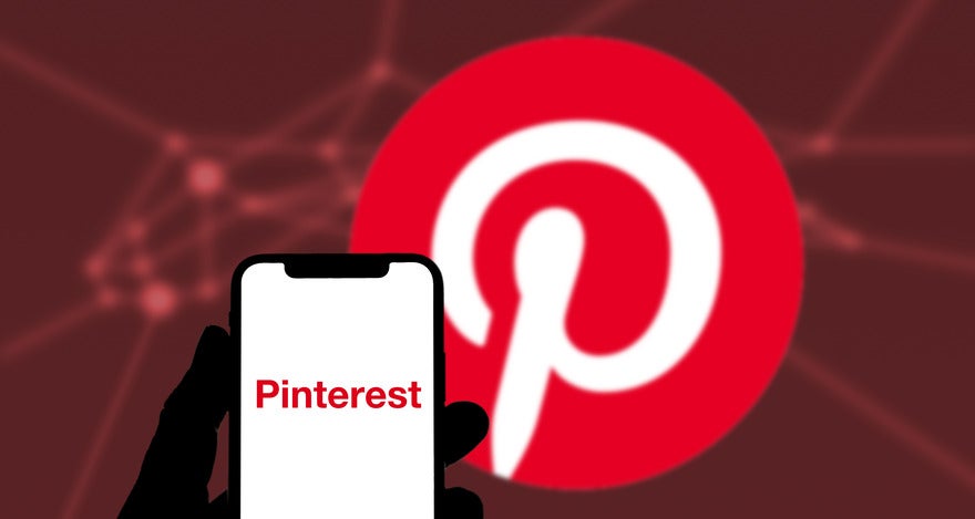 Wix Pinterest Integration Intro A hand holds a smartphone displaying the Pinterest logo, set against a blurred, red-backgrounded Pinterest symbol.