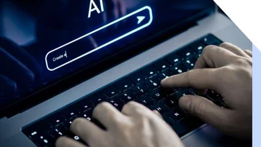 A person types on a laptop keyboard with a dark screen displaying "AI" and a search bar, suggesting an interaction with artificial intelligence.