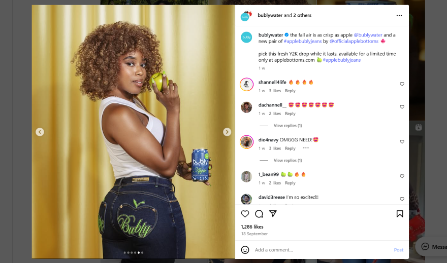 A person holds a green apple and a can of Bubly sparkling water, wearing stylish denim with "Bubly" embroidered on the back.
