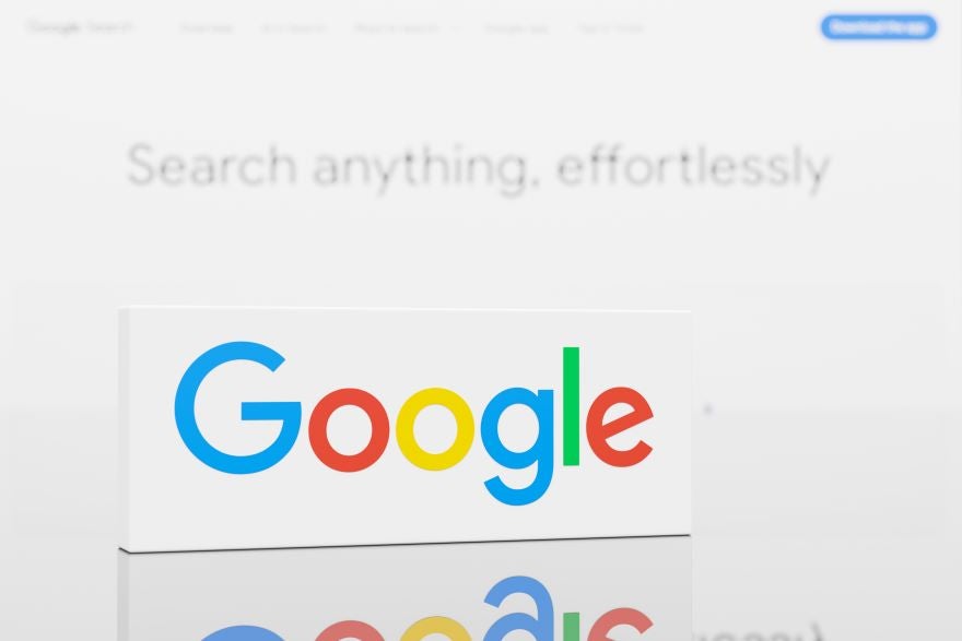 Close-up of Google logo on a white background with the text "Search anything, effortlessly" blurred in the rear.