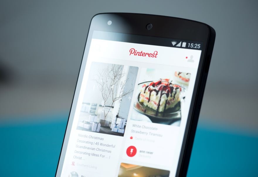 A smartphone displaying the Pinterest app, featuring holiday decor ideas and a dessert recipe, showcased on a colorful interface.