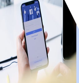 Person holding a phone showing the Facebook login