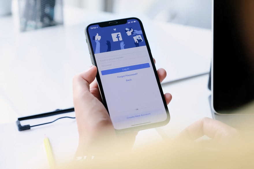 Should your business use Facebook Person holding a phone showing the Facebook login