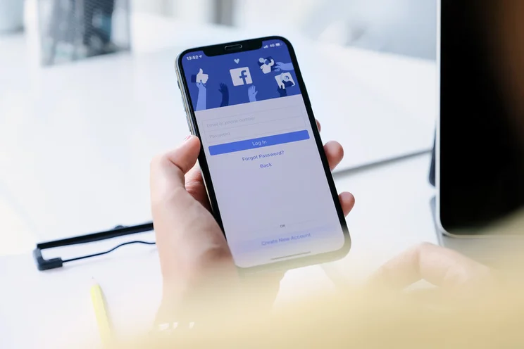 Person holding a phone showing the Facebook login
