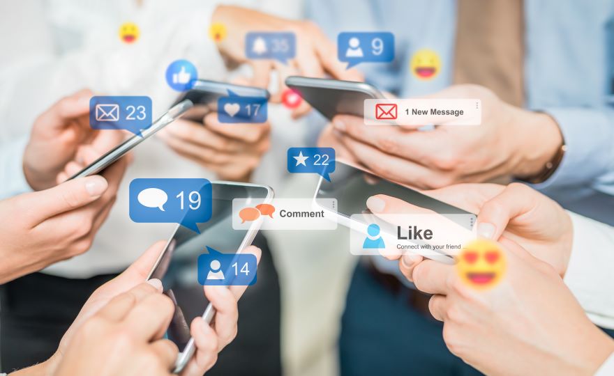 A close-up of hands using smartphones, surrounded by social media notifications, emojis, and interaction icons.