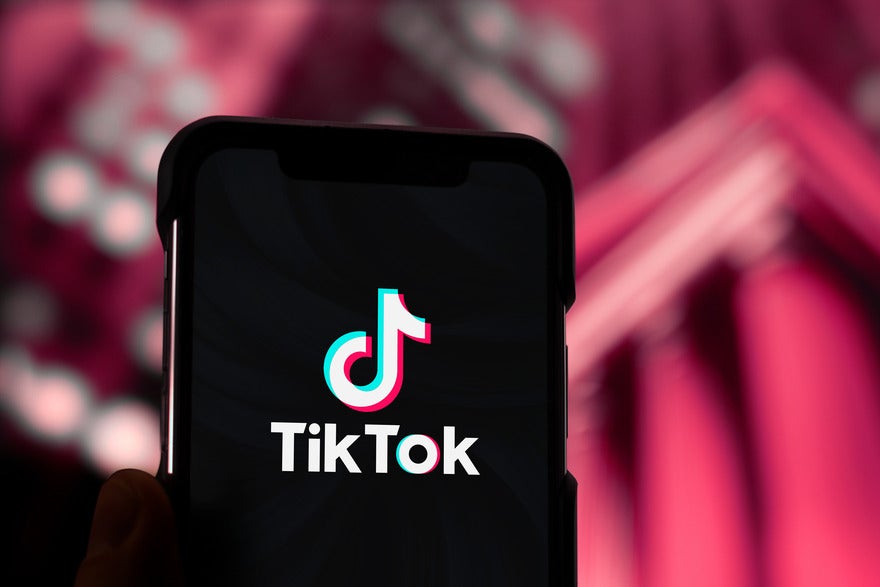 Trending TikTok hashtags Mobile phone with TikTok logo, held against a red backdrop