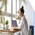 Woman working at her laptop on a desk by a large window