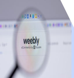 Weebly logo on a desktop visible under a magnifying glass