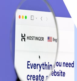 Magnifying glass hovering over the Hostinger logo on the desktop homepage