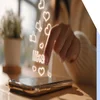 A hand pressing a smartphone screen with glowing "like" and heart icons emerging, symbolizing social media interaction.