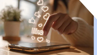 A hand pressing a smartphone screen with glowing "like" and heart icons emerging, symbolizing social media interaction.