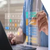 Digital image of a calendar and colour coded checklist floating above a laptop with a hand pointing to the list with a stylus