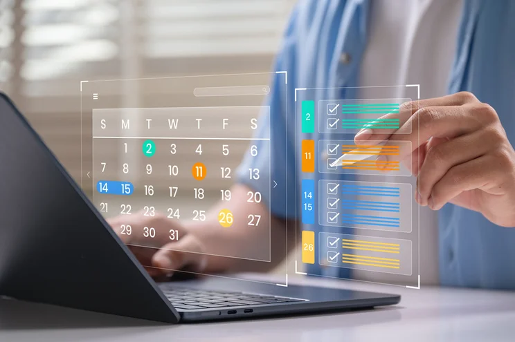 Digital image of a calendar and colour coded checklist floating above a laptop with a hand pointing to the list with a stylus