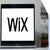 A close-up of a MacBook Air displaying the Wix logo on its screen, with a blurred background of bookshelves.